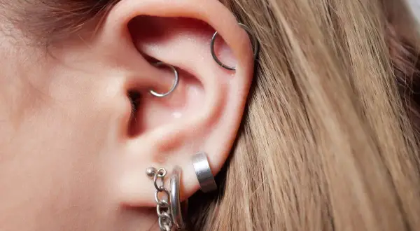 Ucho z kilkoma kolczykami, w tym modnym daith piercingiem.