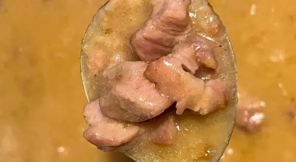 Łyżka pełna soczystej karkówki w sosie, gotowa do podania. Aromatyczne danie, które rozpływa się w ustach.