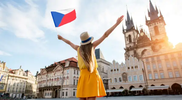 Kobieta z flagą Czech na Rynku Staromiejskim w Pradze. Słowa po czesku, radość podróżowania.