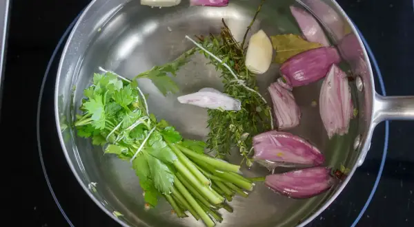 Préparation d'un court-bouillon avec oignons, ail, thym, persil et laurier. Idéal pour le temps de cuisson seiche au court-bouillon.