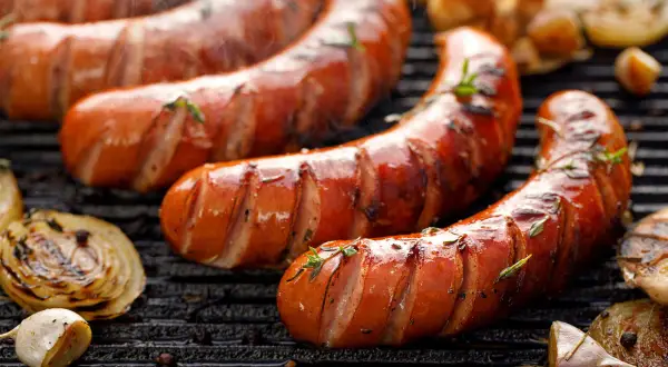 Soczysta kiełbasa śląska z grilla, parująca i pachnąca. Obok grillowana cebula i czosnek. Idealna na letnie wieczory, choć warto sprawdzić kiełbasa śląska kcal.