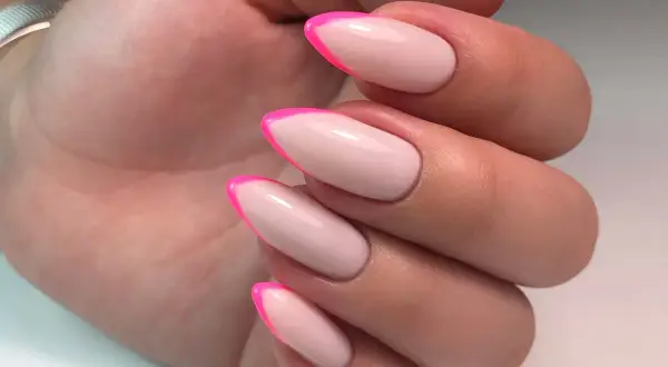 Manucure française tendance avec des pointes rose vif sur une base nude. Un look audacieux et chic.