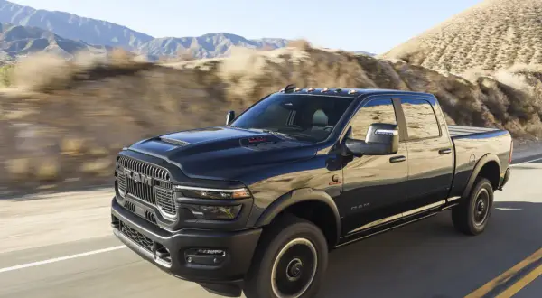 Czarny Dodge Ram 2500 pędzi po pustynnej drodze, góry w tle.