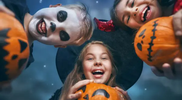Barn med pumpor och utklädnader för ett rysligt halloween kalas.