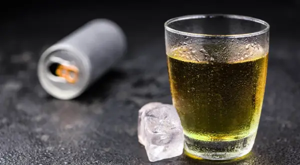 Szklanka z napojem energetycznym i kostki lodu. Czy tauryna pobudza? Ten napój może pomóc.
