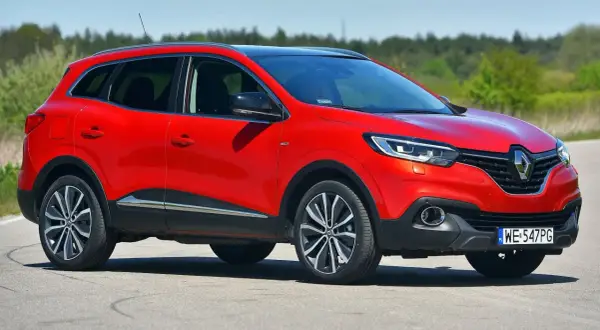 Czerwony Renault Kadjar na drodze. Wiele pozytywnych **renault kadjar opinie** potwierdza jego atrakcyjny wygląd i komfort jazdy.
