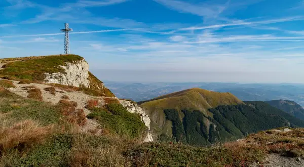 Croce metallica su un crinale roccioso, con vista panoramica sulle colline verdi dell'Emilia Romagna. Perfetto per escursioni.