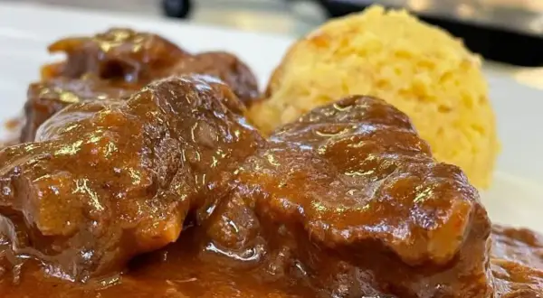 Un saporito gulash trentino, con carne tenera in salsa ricca e una porzione di polenta dorata.