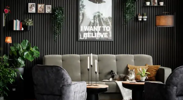 Gemütliches Wohnzimmer mit Akustikpaneelen an der Wand, einem Sofa, Sesseln, Pflanzen und einem Poster. Tolle Akustikpaneele Deko Ideen für ein stilvolles Zuhause.