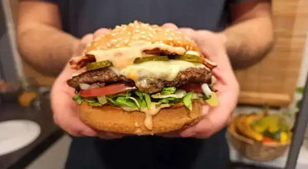 Idealny burger: soczysta wołowina, ser, chrupiąca sałata, pomidor, ogórek i sos. Oto jak składać burgera krok po kroku.