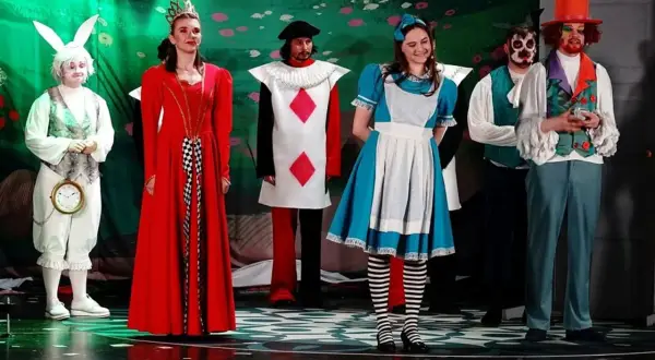 Alicja w Krainie Czarów postacie: Biały Królik z zegarem, Królowa Kier, Walet Kier, Alicja, Szalony Kapelusznik i inni na scenie.