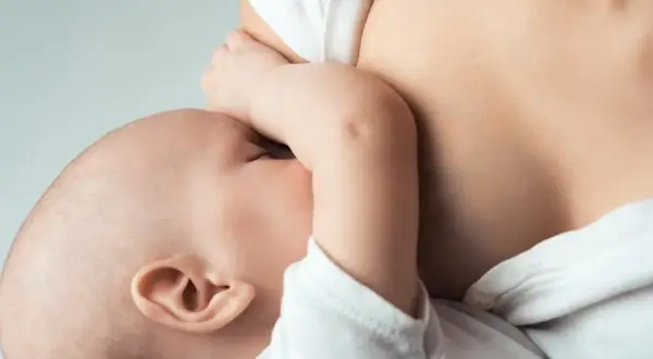Maluszek ssie pierś, co jest naturalnym sposobem na pobudzenie laktacji. Bliskość mamy i dziecka.