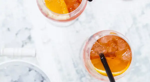 Dwa orzeźwiające drinki Aperol Spritz z plasterkiem pomarańczy i lodem. Idealne na letnie popołudnie.