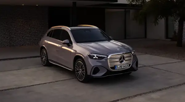 En elegant grå bil Mercedes står parkerad på en uppfart framför ett modernt hus.