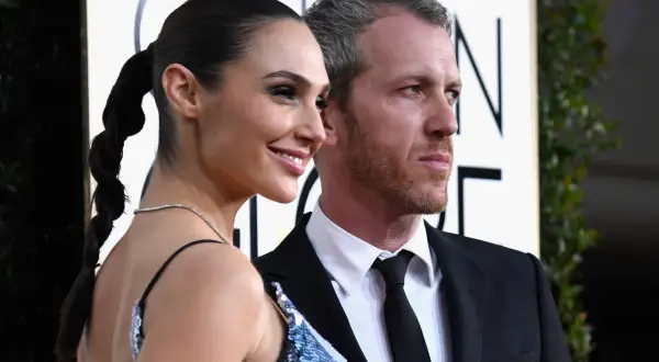 Yaron Varsano y su esposa, Gal Gadot, posan sonrientes en la alfombra dorada.