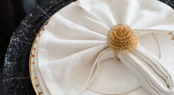 Vackert vika servetter med en gyllene ring som dekoration, redo för en festlig middag.