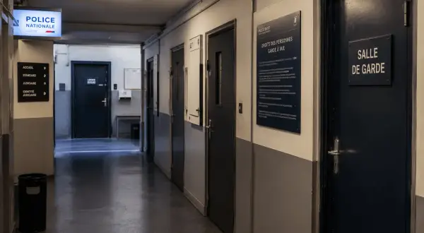 Couloir de commissariat avec des portes et un panneau "Droits des personnes en garde à vue". La fin de garde à vue approche pour certains.