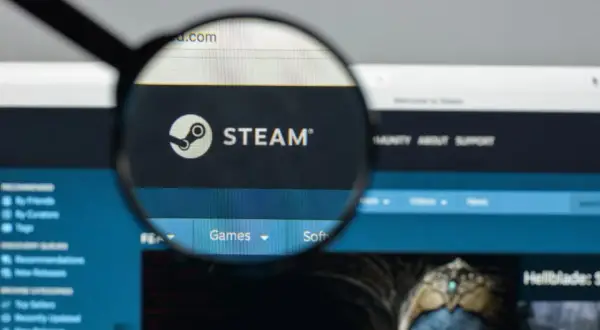 Lupa powiększa logo Steam i fragment strony internetowej platformy z grami.