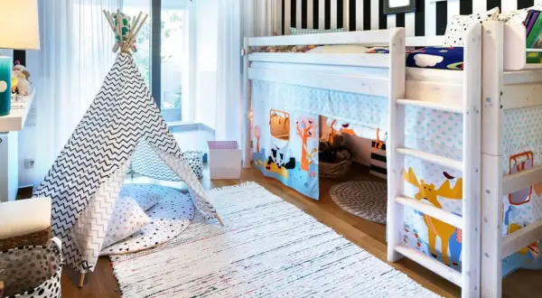 Ein **hochbett vor fenster** in einem Kinderzimmer mit Spielzelt, Teppichen und bunten Vorhängen.