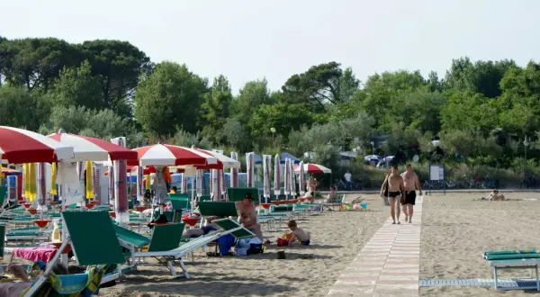 Plaża w Caorle, Santa Margherita. Rzędy parasoli i leżaków, ludzie odpoczywają. Idealne miejsce na camping.