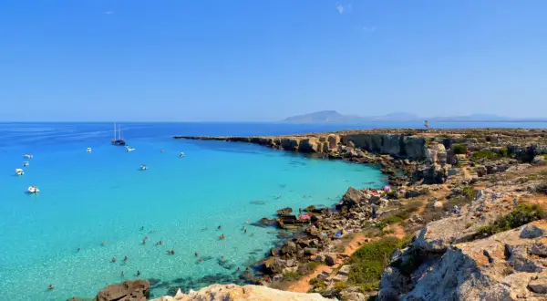 La spiaggia più bella di Favignana: acque cristalline, scogliere dorate e barche all'ancora. Un paradiso terrestre.