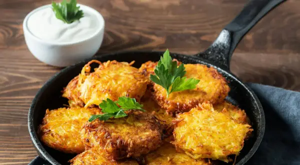 Goldbraune Kartoffelpuffer im Gusseisenpfännchen, perfekt für ein Kartoffelpuffer Rezept. Dazu ein Schälchen cremiger Dip.
