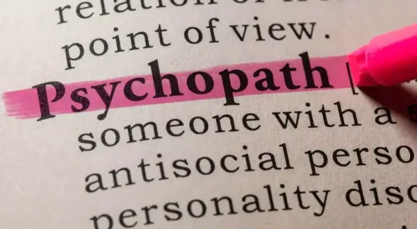 Słowo "psychopata" podkreślone różowym zakreślaczem w słowniku. Opisuje osobę z antyspołecznym zaburzeniem osobowości.