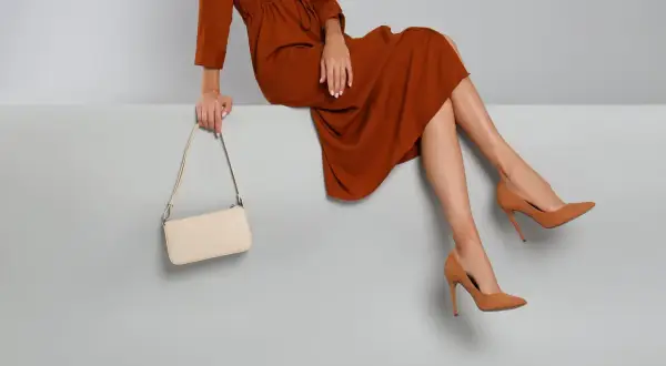 Elegant braunes Kleid, cremefarbene Tasche und braune Pumps – so zieht man in die Oper.