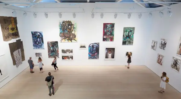 Visitors explore a vibrant exhibition, showcasing bold portraits and mixed media pieces that define the dynamic London art scene.