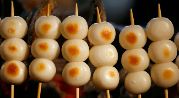 Proste japońskie dania: słodkie kluseczki mochi na patyczkach, lekko przypieczone.