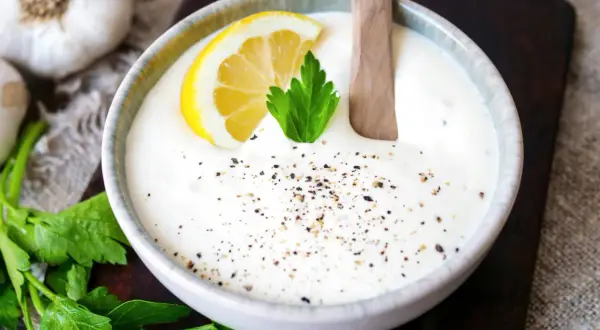 Cremiger knoblauch dip mit Zitrone und Petersilie, bestreut mit Pfeffer. Perfekt zum Dippen!