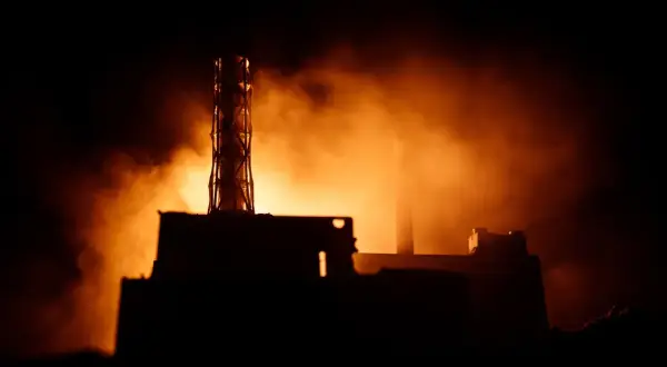 Mroczna sylwetka elektrowni, unosząca się mgła i pomarańczowe światło przywołują pamięć o tym, co wydarzyło się w Czarnobylu.