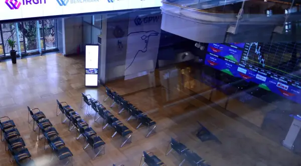 Sala konferencyjna z rzędami krzeseł, na ekranach widoczne dane giełdowe, w tym knf rejestr pozycji krótkich.