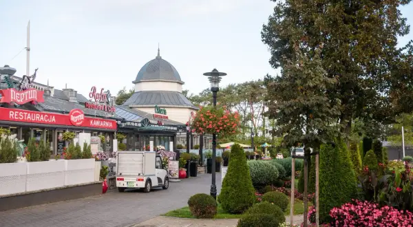 Urokliwy deptak w Międzyzdrojach, gdzie restauracje i kawiarnie zapraszają do odpoczynku. Wśród zieleni i kwiatów, to idealne miejsce na spacer i odkrywanie międzyzdrojskie atrakcje.