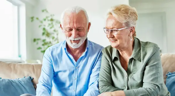 Uśmiechnięta para seniorów sprawdza w internecie, ile wynosi renta inwalidzka w Niemczech.