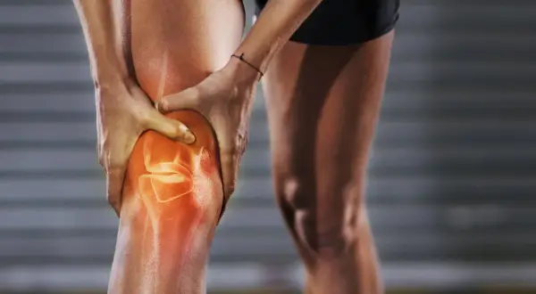 Sportlerin hält schmerzendes Knie. Rote Hitze zeigt Entzündung im Bereich der Kniekehle, die beim Laufen Probleme macht.