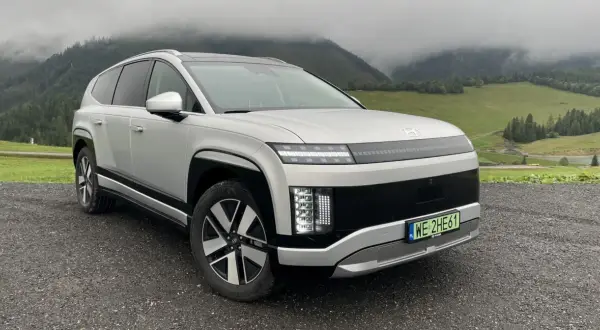 Srebrny Hyundai Ioniq 9 na tle mglistych gór i zielonych łąk.