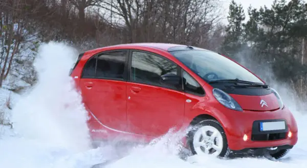 Röd Citroën C-Zero kör genom snö, skapar en stor snövirvel.