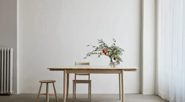 Ett ljust såpa ekbord med en vas med blommor och en pall.
