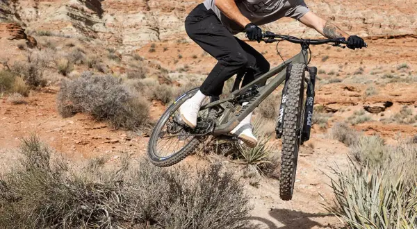 Mountainbiker auf einem Canyon Nerve AL 8.0 im Sprung in einer staubigen Wüstenlandschaft.