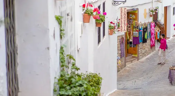 Calle estrecha en el centro de Almería, con casas blancas, flores y una tienda de ropa.