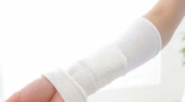 Ramię owinięte bandażem, opatrunek na ranę po operacji.