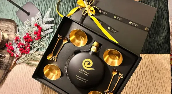 Elegante confezione regalo con olio d'oliva extra vergine, coppette e cucchiaini dorati. Regalare olio d'oliva ha un significato di benessere e cura.