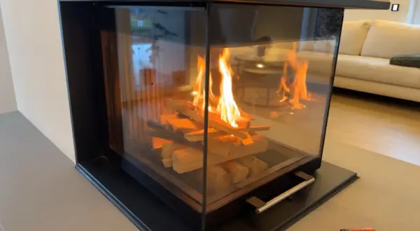 Ein moderner Kamin mit brennendem Holz. Die Flammen tanzen und geben ein warmes Licht ab, das die Frage aufwirft, wie lange brennt ein holzscheit wohl?