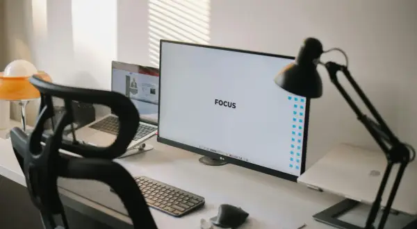 Ein aufgeräumter Schreibtisch mit dem Wort "FOCUS" auf dem Monitor, der eine "clean desk policy" verkörpert.