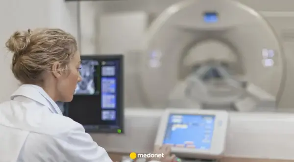 Lekarka w białym fartuchu analizuje obraz z rezonansu magnetycznego na monitorze.