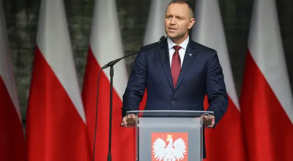 Mężczyzna w garniturze przemawia na tle flag Polski. Może właśnie użył swojego prawa weta.