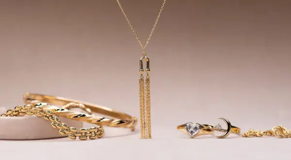 Elegantes conjuntos de oro para mujer: brazaletes, un collar con flecos dorados y anillos con forma de corazón y luna.