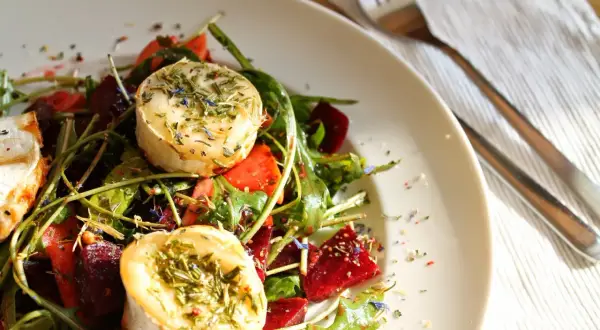 Ein köstlicher Rote Bete Salat mit Ziegenkäse, garniert mit Kräutern und Blüten.