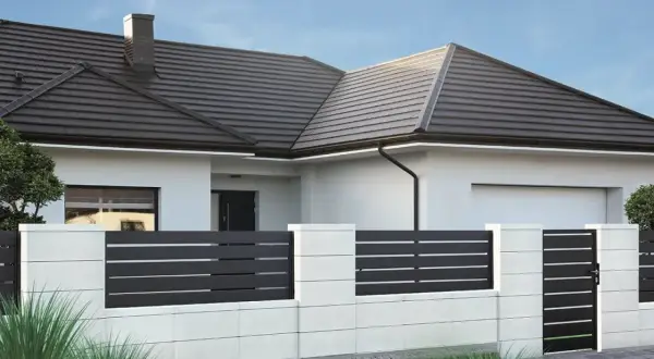 Nowoczesne płoty betonowe w kolorach białym i grafitowym otaczają dom z brązowym dachem.